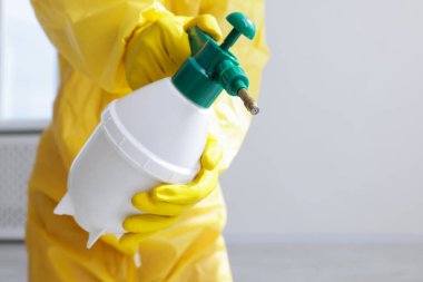 Koruyucu kıyafetli haşereci böcek ilacı sıkıyor, yakın plan.