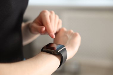 Kadın spor salonunda spor yaparken takip cihazını kontrol ediyor, yakın plan. Metin için boşluk