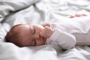 Sevimli yeni doğmuş bebek yatakta uyuyor, yakın plan.