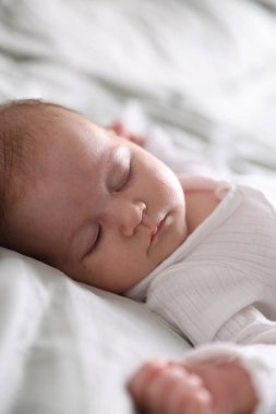 Sevimli yeni doğmuş bebek yatakta uyuyor, yakın plan.