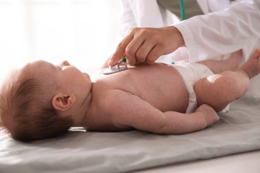 Klinikteki masada steteskopla bebeği muayene eden çocuk doktoru.