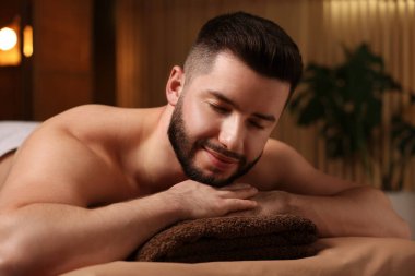 Güzellik salonunda masaj masasında yatan yakışıklı adam.