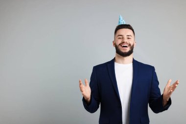 Doğum günün kutlu olsun. Gri arkaplanda parti şapkası olan yakışıklı bir adam, mesaj için yer
