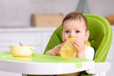 Evdeki yemek sandalyesinde biberonu olan şirin bir bebek. Metin için boşluk