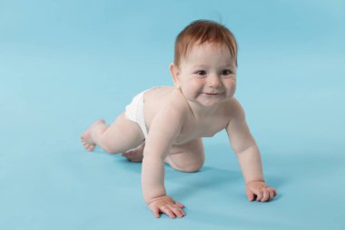 Açık mavi arka planda emekleyen şirin bir bebek.