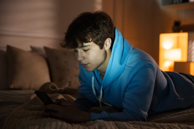 Ergen çocuk evde akıllı telefon kullanıyor.