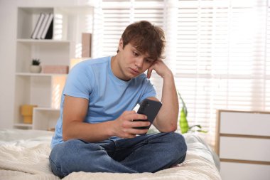Ergen çocuk evde akıllı telefon kullanıyor.