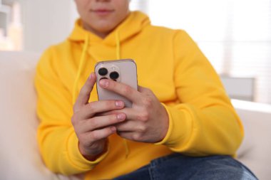 Ergen çocuk evde akıllı telefon kullanıyor, yakın plan.