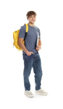 Sırt çantası ve beyaz arka planda defterleri olan sevimli bir genç çocuk.