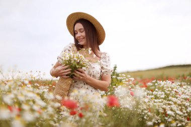 Gülen kadın şapkalı, papatya çiçekli yaban çiçeği çayırında