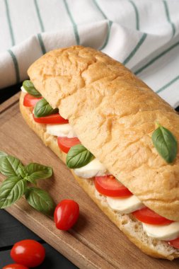 Mozarella peynirli, domatesli, fesleğenli, siyah ahşap masa, yakın plan.