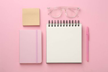 Not defterleri, yapışkan notlar, pembe arka planda gözlük ve kalem, düz konum