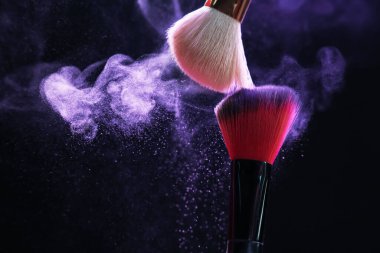 Siyah arka planda mor göz farlı makyaj fırçaları, yakın plan. Metin için boşluk