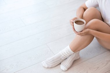 Kahveli kadın sıcak zeminde oturuyor, yakın plan. Isıtma sistemi