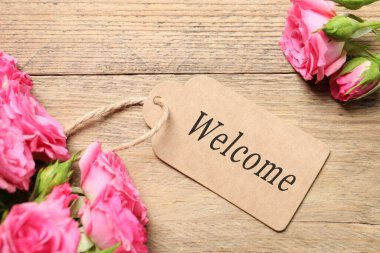 Hoş geldin kartı ve güller ahşap arka planda, üst manzara