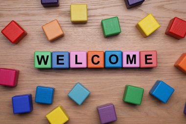 Kelime Hoş Geldiniz Tahta masanın üzerinde renkli küplerden yapılmış, düz yatıyordu