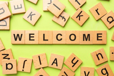 Kelime Hoş geldiniz açık yeşil arka planda tahta küplerden yapılmış düz yatıyordu