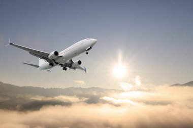 Güneşli bir sabahta dağların üzerinden uçan bir uçak.