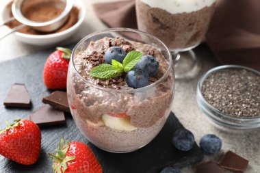 Çikolatalı puding, chia tohumu, çilek ve böğürtlen açık gri masada, yakın plan.