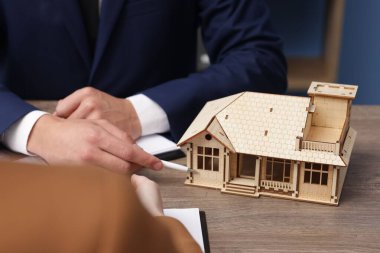 Ofiste ev modeliyle aynı masada çalışan bir emlakçı. Yakın plan.