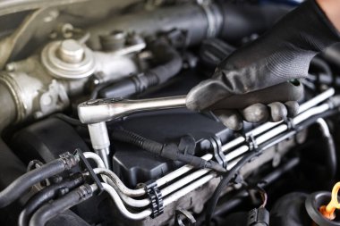 Otomobil parçaları. Tork anahtarı olan profesyonel bir tamirci, kapalı alanda araba tamir ediyor, yakın plan.