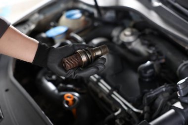 Otomobil parçası. Kaputun içinde açık kaputun yanında sürücü mili olan profesyonel bir tamirci, yakın plan. Metin için boşluk