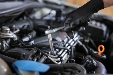 Otomobil parçaları. Tork anahtarı olan profesyonel bir tamirci, kapalı alanda araba tamir ediyor, yakın plan.