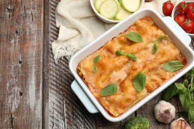 Pişirme kabında leziz vejetaryen lazanya ve ahşap masada malzemeler, düz yatak. Metin için boşluk