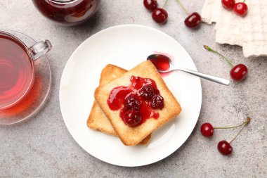 Lezzetli kiraz reçelli tostlar, çay ve gri masada taze meyveler, düz uzanma