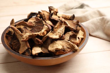 Kurumuş mantar parçaları açık tahta masada kasede, yakın plan.