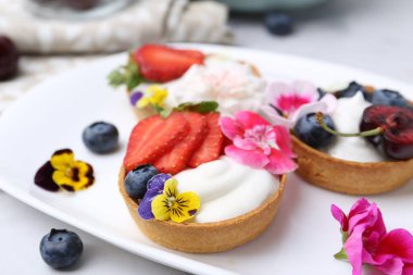 Böğürtlenli ve çiçekli tartlar, yakın plan. Tatlı nefis.