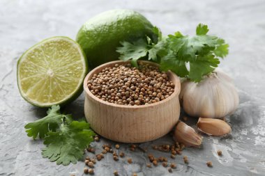 Kişniş tohumu, taze kişniş, kireç ve sarımsak gri desenli masa, yakın plan.