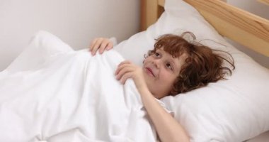 Evdeki battaniyenin altında saklanan küçük çocuk.