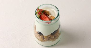 Mısır gevrekli yoğurt ve beyaz masada cam kavanozda böğürtlen.