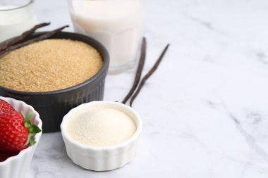 Panna cotta için farklı malzemeler. Süt, şeker, vanilya ve çilek beyaz mermer masada, yakın plan. Metin için boşluk