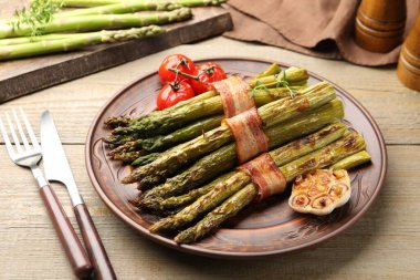 Ahşap masada domuz pastırması ile servis edilen lezzetli kuşkonmaz, yakın plan.