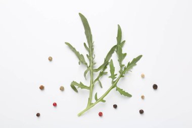 Taze yeşil roka yaprakları ve beyaz arka planda biberler, düz yatıyordu.