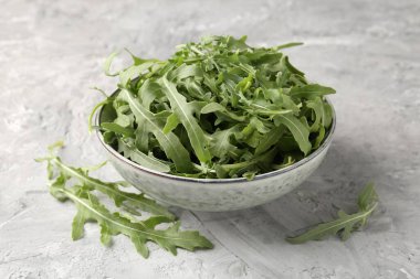 Taze yeşil roka yaprakları kasede gri masada, yakın plan.