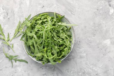 Taze yeşil roka yaprakları gri masada kasede, düz yerde. Metin için boşluk