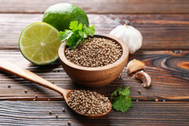 Kişniş tohumu, taze kişniş, kireç ve sarımsak ahşap masada, yakın plan.