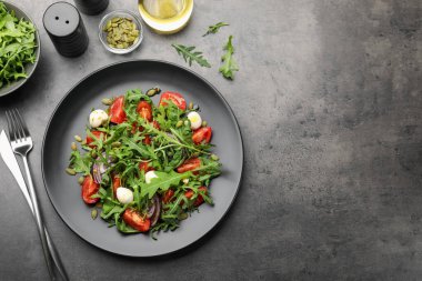 Lezzetli salata roka, mozzarella ve sebzeler gri masada servis edilir. Metin için boşluk