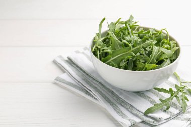 Taze yeşil roka yaprakları kasede beyaz ahşap masada, yakın plan. Metin için boşluk