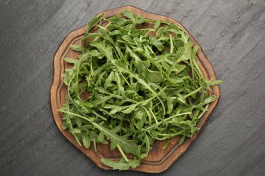 Taze yeşil roka yaprakları siyah masanın üstünde, üst tarafta.