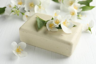 Sabun barı ve yasemin çiçekleri beyaz ahşap masada, yakın plan.