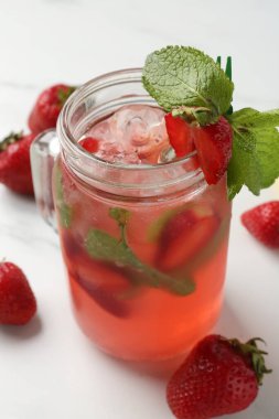 Çilekli, buzlu ve naneli içecek beyaz masada, yakın plan.