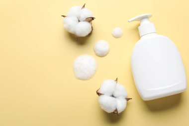 Düz kompozisyon, sarı zemin üzerinde sıvı sabun ve pamuk çiçekleri vardı. Metin için boşluk