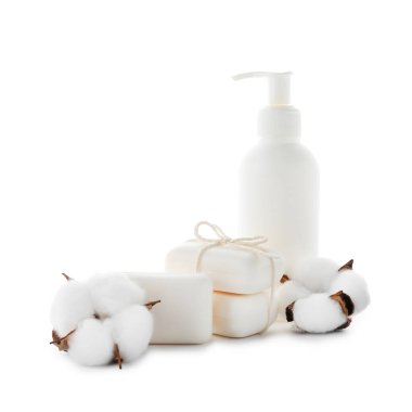 Sabun çubukları, bir şişe cilt ürünü ve beyaz üzerine izole edilmiş pamuk çiçekleri.