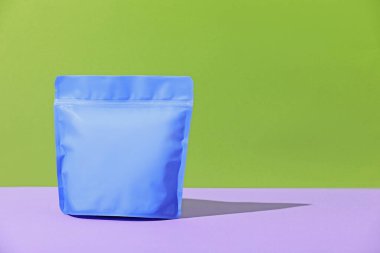 Menekşe masasının üzerinde yeşil arka planda duran fermuar stand-up kesesi. Tasarım için model