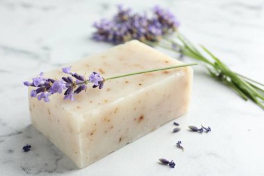 Sabun çubuğu ve lavanta çiçekleri beyaz mermer masada, yakın plan.
