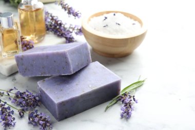 Sabun barları, diğer kozmetik ürünleri ve lavanta çiçekleri beyaz mermer masada, yakın plan. Metin için boşluk